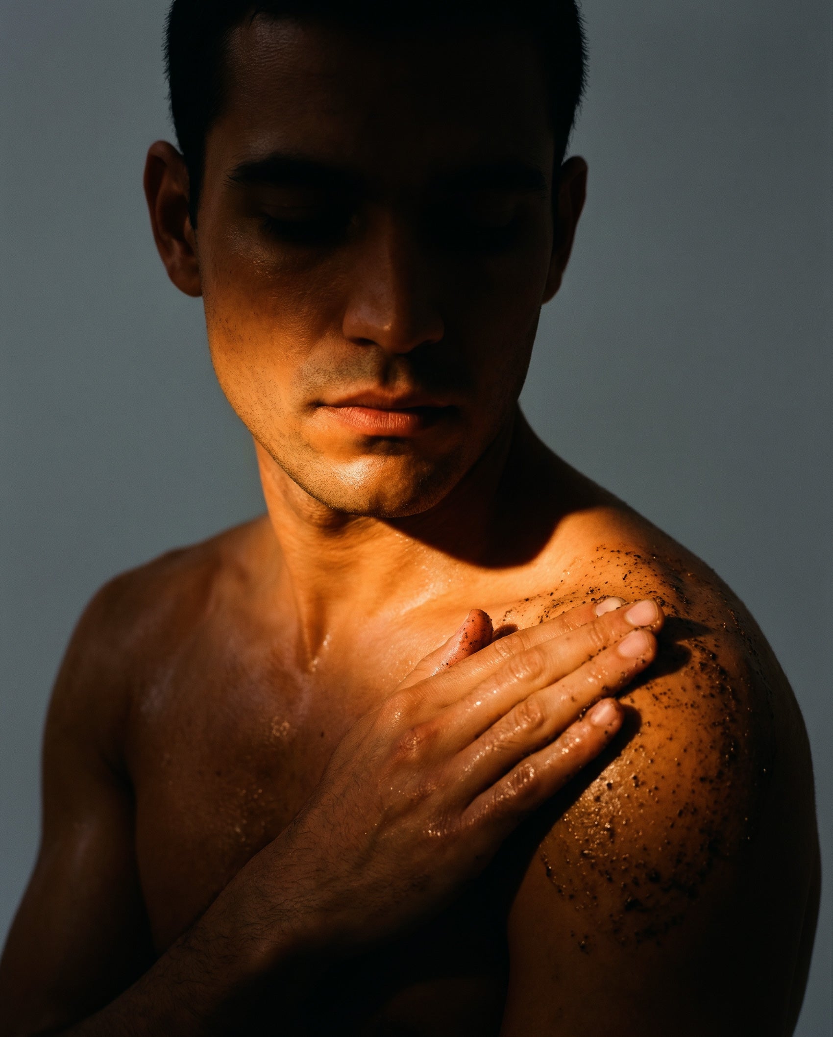 man applying body exfoliant scrub to shoulders, leaving his skin smooth and hydrated